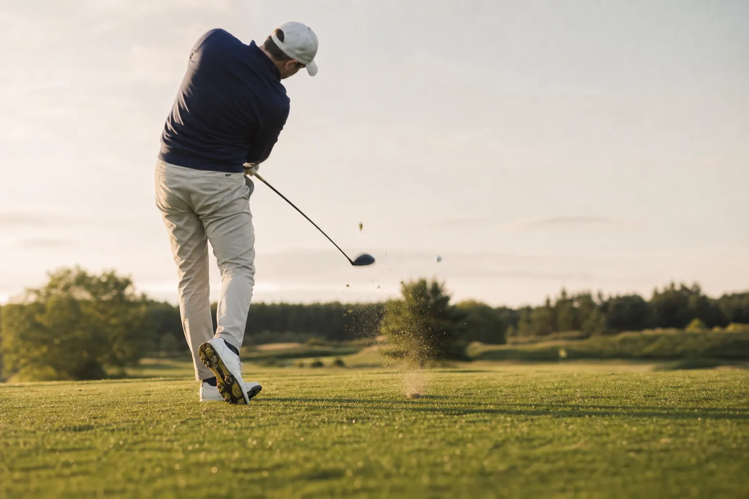 En golfare i sving med en driver på tee, precis i träffögonblicket