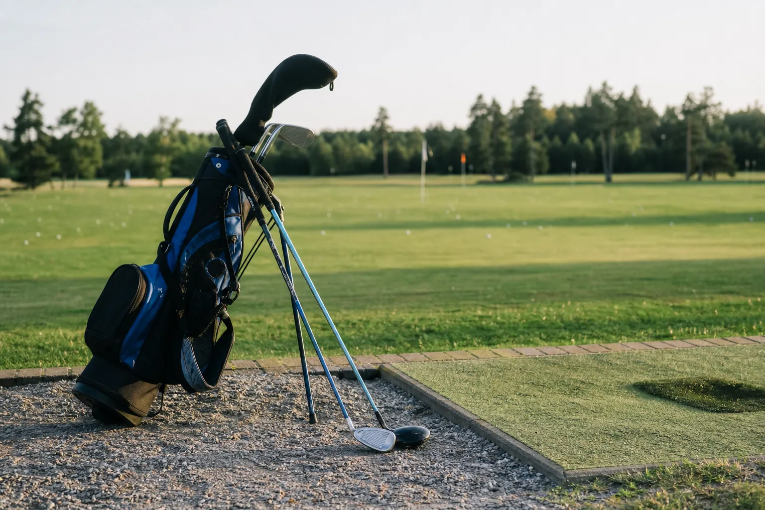 Ett juniorset i barnstorlek lutat mot en liten golfbag på en driving range