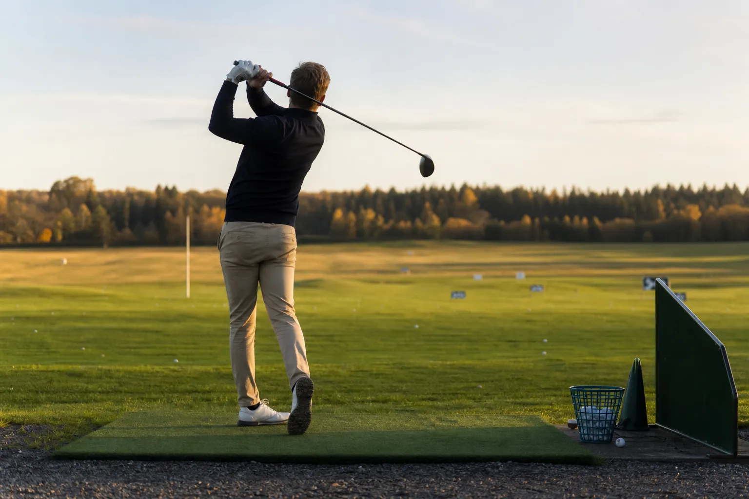 Vänsterspelare gör ett utslag med en golfklubba på en driving range