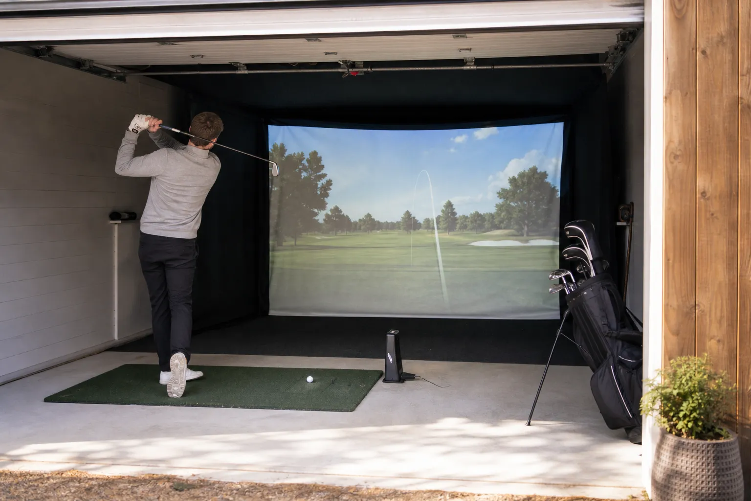 Hemmagolfsimulator i ett garage med impactskärm och projicerad bana